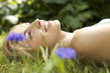 Close-up portrait of young woman lying in grass with flowers