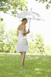 Portrait of young woman walking in grass holding an umbrella