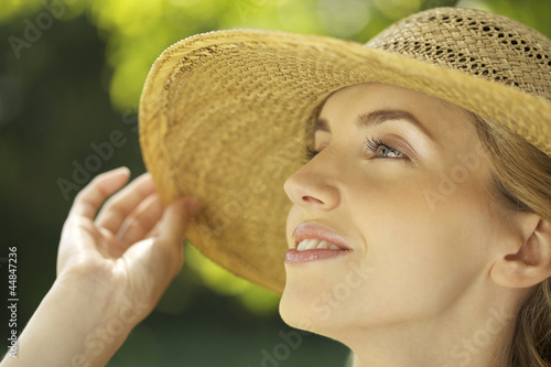 Photo: Close-up portrait of young woman in straw hat outdoors Close-up portrait of young woman in straw hat outdoors
