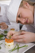 Trainee garnishing food in commercial kitchen