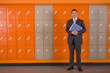 Teacher holding paperwork standing near school lockers