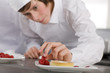 Trainee garnishing dessert in commercial kitchen