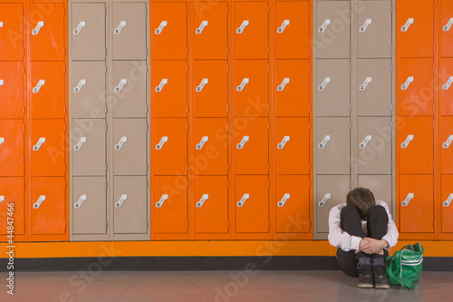 Photo: Unhappy student sitting on floor near school lockers Unhappy student sitting on floor near school lockers