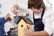Foto: Student attaching roof to birdhouse in woodworking class Student attaching roof to birdhouse in woodworking class