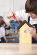 Foto: Student attaching roof to birdhouse in woodworking class Student attaching roof to birdhouse in woodworking class