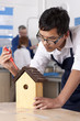 Foto: Student attaching roof to birdhouse in woodworking class Student attaching roof to birdhouse in woodworking class