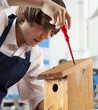 Foto: Student attaching roof to birdhouse in woodworking class Student attaching roof to birdhouse in woodworking class