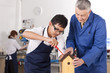 Photo: Teacher explaining to student how to attach roof to birdhouse in woodworking class Teacher explaining to student how to attach roof to birdhouse in woodworking class