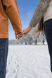 Close up of couple holding hands in snowy field