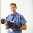 Portrait of smiling doctor holding newborn baby boy in hospital