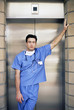 Portrait of serious doctor leaning on wall in front of elevator
