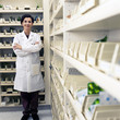 Foto: Portrait of smiling pharmacist in lab coat with arms crossed in pharmacy Portrait of smiling pharmacist in lab coat with arms crossed in pharmacy