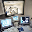 Photo: Data and MRI scan on computers with doctor looking over patient in MRI scanner in background Data and MRI scan on computers with doctor looking over patient in MRI scanner in background