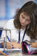 Close up of girl taking notes near Bunsen burner in science class