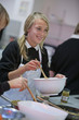 Smiling girl with wooden spoon and bowl cooking in home economics class
