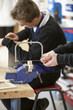 Boy using saw to cut wood in classroom workshop