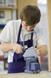 Boy using saw in school workshop