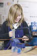 Girl using saw in school workshop