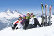 Foto: Portrait of smiling senior couples with skis sitting on snowy mountain Portrait of smiling senior couples with skis sitting on snowy mountain