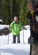 Smiling couple with ski poles trekking in snowy woods