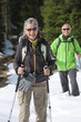 Portrait of smiling couple with ski poles trekking in snowy woods