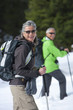Portrait of smiling couple with ski poles and backpacks trekking in snowy woods