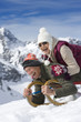 Smiling senior couple sledding on snowy mountain