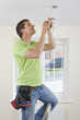 Electrician installing overhead light with compact fluorescent light bulb