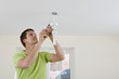 Photo: Electrician installing overhead light with compact fluorescent light bulb Electrician installing overhead light with compact fluorescent light bulb