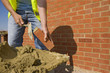 Bricklayer applying mortar to brick with trowel