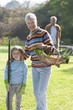 Portrait of grandmother and granddaughter gardening with man in background
