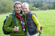 Portrait of smiling senior couple backpacking in field