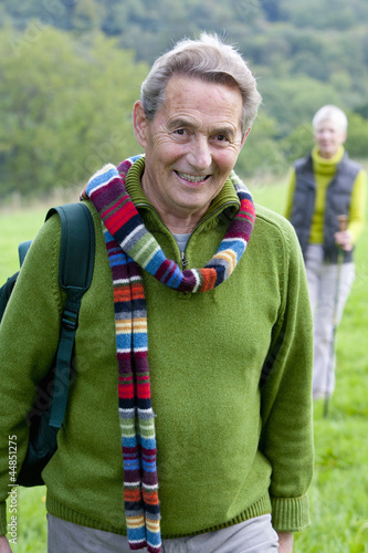 Photo: Portrait of smiling senior couple backpacking in field Portrait of smiling senior couple backpacking in field