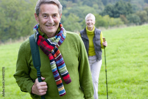 Photo: Portrait of smiling senior couple backpacking in field Portrait of smiling senior couple backpacking in field