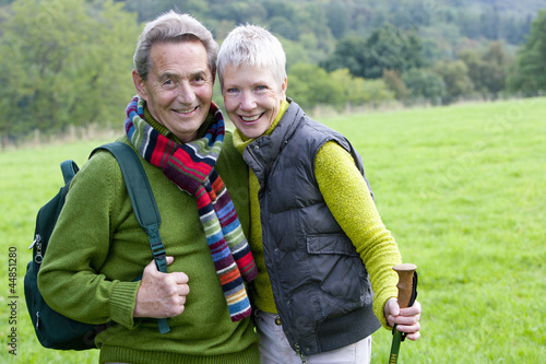 Photo: Portrait of smiling senior couple backpacking in field Portrait of smiling senior couple backpacking in field