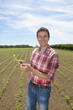 Portrait of smiling farmer holding corn seedling in field