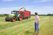 Farmer watching tractors harvest hay in field