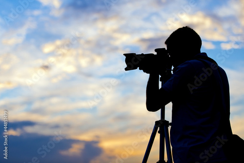 Photo: Silhouette of a photographer taking a picture in sunset Silhouette of a photographer taking a picture in sunset