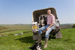 Portrait of shepherd with dog sitting on tailgate of truck