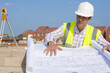 Architect reviewing blueprints at construction site