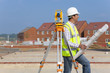 Architect with blueprints and theodolite at construction site