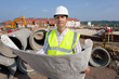Photo: Portrait of architect holding blueprints at construction site Portrait of architect holding blueprints at construction site
