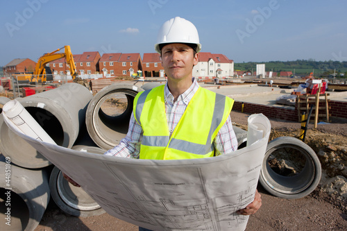 Photo: Portrait of architect holding blueprints at construction site Portrait of architect holding blueprints at construction site