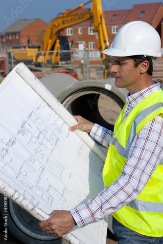 Photo: Architect reviewing blueprints at construction site Architect reviewing blueprints at construction site