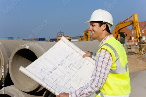 Photo: Architect reviewing blueprints at construction site Architect reviewing blueprints at construction site