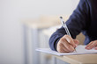 Close up of male student taking exam at desk in classroom