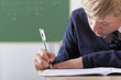 Photo: Close up of male student in school uniform taking exam at desk in classroom Close up of male student in school uniform taking exam at desk in classroom