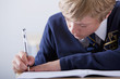 Photo: Close up of male student in school uniform taking exam at desk in classroom Close up of male student in school uniform taking exam at desk in classroom