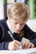 Photo: Close up of male student in school uniform taking exam at desk in classroom Close up of male student in school uniform taking exam at desk in classroom