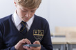 Photo: Close up of male student in school uniform using calculator Close up of male student in school uniform using calculator